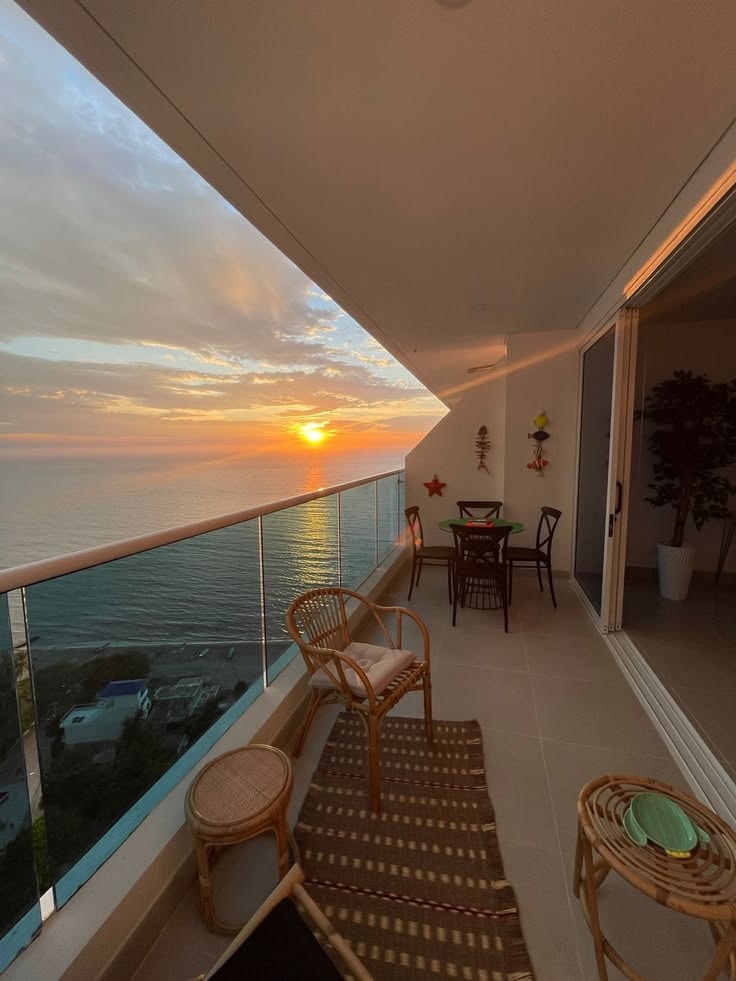 Varanda organizada com mobiliário e vista para o mar ao pôr do sol